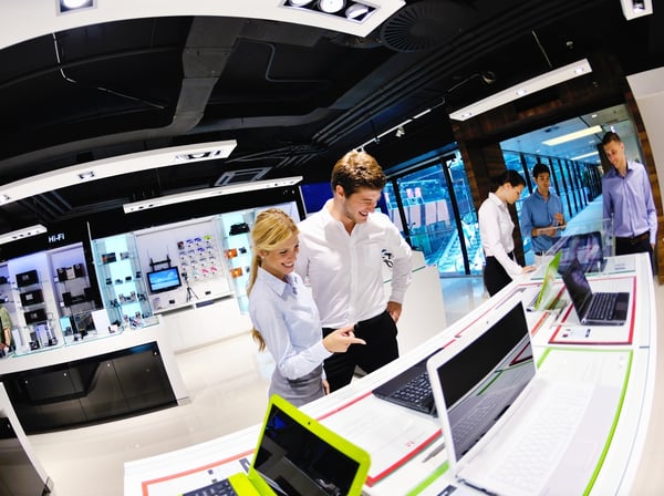 Young couple in consumer electronics store looking at latest laptop, television and photo camera